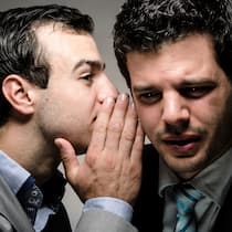 So halten Sie Ihr Risiko klein Ein Mann flüstert einem anderen Mann etwas ins Ohr