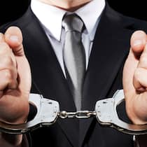 Was für Beschuldigte und Opfer gilt Ein Mann in Anzug trägt Handschellen. Verschaffen Sie sich einen Überblick, wie in der Schweiz ein Strafverfahren generell abläuft.