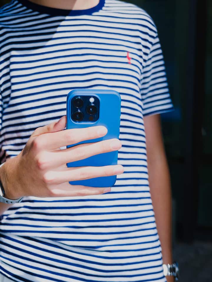 So unterstützen Sie Ihr Kind auf Social Media Ein Jugendlicher hält ein Smartphone vor seiner Brust.