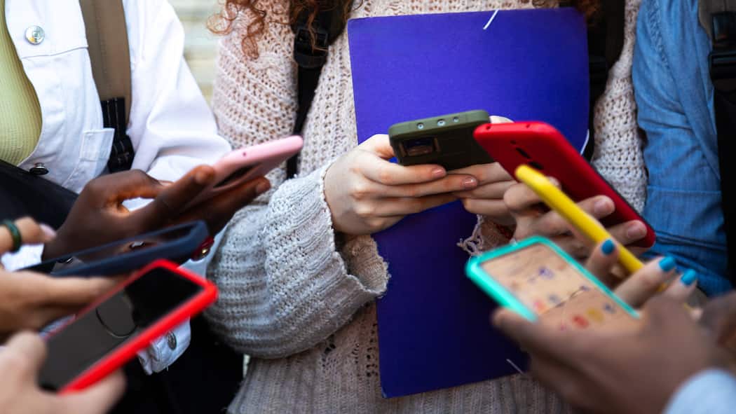 Social-Media-Verbot für Jugendliche in der Schweiz chancenlos Close up of young college students hands holding mobile phones. Teenagers addicted to smartphones and technology. Group of friends sharing content on social media. Technology concept.