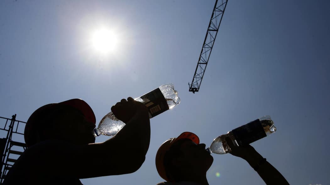 Hitzefrei existiert nicht – doch diese Regeln müssen Arbeitgeber befolgen Zwei Bauarbeiter trinken aus Wasserflaschen. Hohe Temperaturen machen die Arbeit beschwerlich. Wer kann hitzefrei machen? Eine Übersicht.