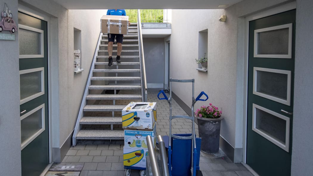 Finderlohn für Wohnung verärgert Mitbewerber Umzugsszene, Mann steigt mit Kiste eine Treppe hoch - Der Wohnungsmarkt ist umkämpft. Dass sich manche Umzugswillige mit Geld einen Startvorteil verschaffen, kommt schlecht an. Was denken Sie darüber? Diskutieren Sie mit