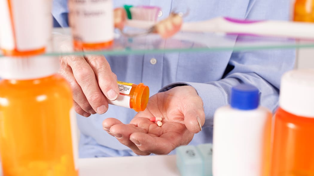 Weniger ist meist besser Ein Mann nimmt ein Medikament aus dem Spiegelschrank.