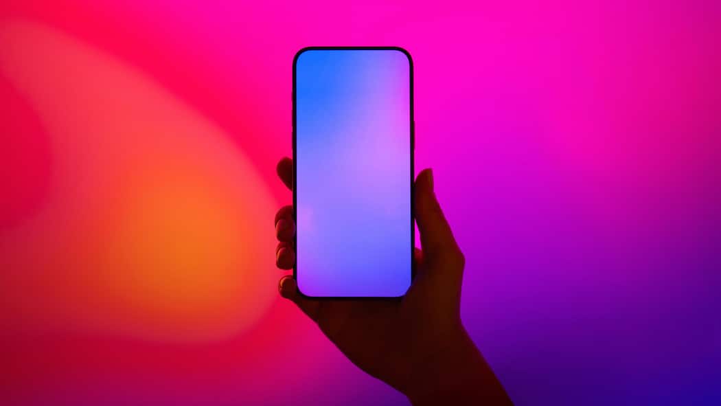 Ein neues Handy für mehr Lebensqualität Close-up shot of a female hand holding smartphone with blank screen against illuminated LED digital display screen. Mockup image. Connecting to the future. Futuristic. Artificial intelligence. Innovation and technology concept2203621915