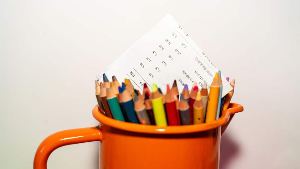 Dank Spenden die Schulden reduziert – und einen Neubeginn ermöglicht Invoice in an orange jar of colored pencils on white background with copy space