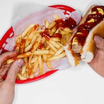 Ungesunde Snacks machen süchtig wie Zigaretten Eine Person isst Pommes Frittes und Burger. Chips, Tiefkühlpizza und Softdrinks können nicht nur krank machen. Sondern auch süchtig.