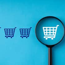 Künstliche Intelligenz erkennt unseriöse Webshops Eine Lupe vor vier blauen und einem weissen Einkaufswagen auf blauem Hintergrund. Künstliche Intelligenz auf fakeshopfinder.de erkennt unseriöse Webshops.