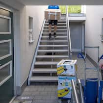 Finderlohn für Wohnung verärgert Mitbewerber Umzugsszene, Mann steigt mit Kiste eine Treppe hoch - Der Wohnungsmarkt ist umkämpft. Dass sich manche Umzugswillige mit Geld einen Startvorteil verschaffen, kommt schlecht an. Was denken Sie darüber? Diskutieren Sie mit