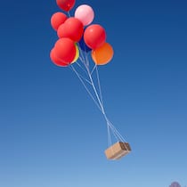 Bestellt in der Schweiz – geliefert von irgendwoher Ein Paket schwebt an bunten Ballons durch die Luft.