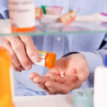 Weniger ist meist besser Ein Mann nimmt ein Medikament aus dem Spiegelschrank.