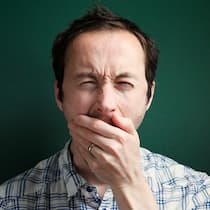 Wie krank macht chronische Übermüdung? Ein übermüdeter Mann gähnt.