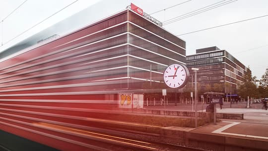 Zu fährt an riesiger SBB Uhr vor dem neuen SBB Hauptsitz in Bern vorbei.