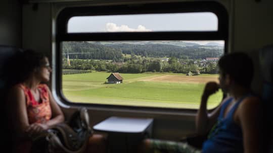 Frau blickt aus fahrendem Zug - Die Beobachter-Redaktion verrät ihre Tricks fürs Pendeln in der Sommerhitze. Und wie gestalten Sie die Fahrt im ÖV erträglicher? Teilen Sie Ihre Tipps in der Kommentarspalte