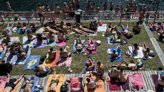 Menschen sonnen sich an der Limmat, aufgenommen am Pfingst-Montag, 9. Juni 2014 am Letten in Zuerich. Das hochsommerliche Wetter am Pfingstwochenende hat den Schweizer Freibaedern einen Besucheransturm beschert. Trotz teilweise noch ziemlich kuehler …