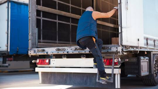 Ein Angestellter klettert in den Laderaum eines Transporters.