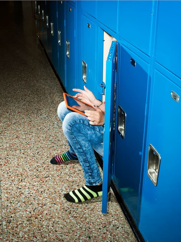 Macht das Handy psychisch krank? Kind sitzt in Schrank und starrt auf Tablet: Machen Handy und soziale Medien psychisch krank? Fakten und Tipps